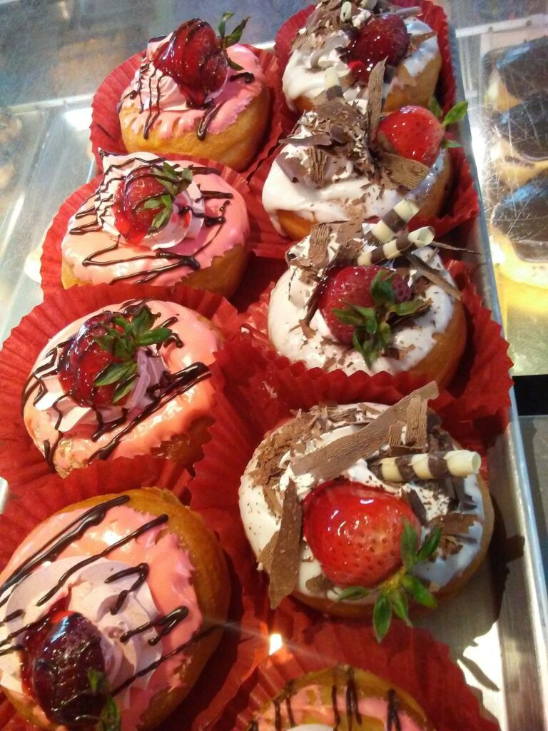 Fancy donuts with strawberries and chocolate drizzle on top.