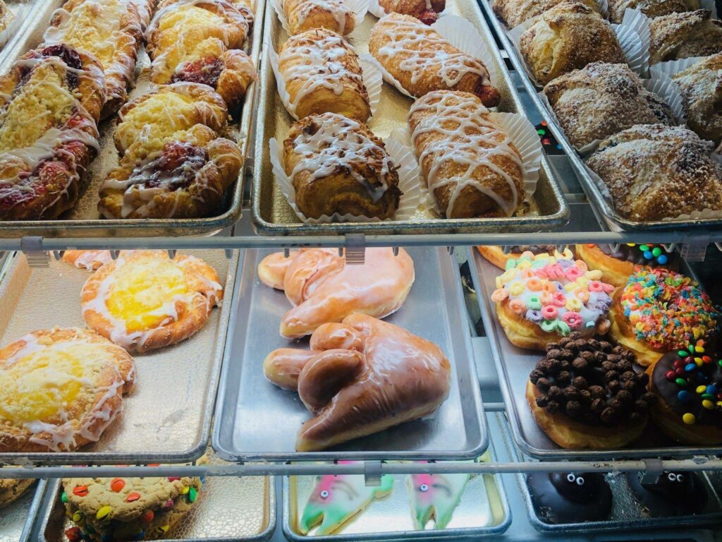 A display case full of a variety of donuts, including the middle finger donut.