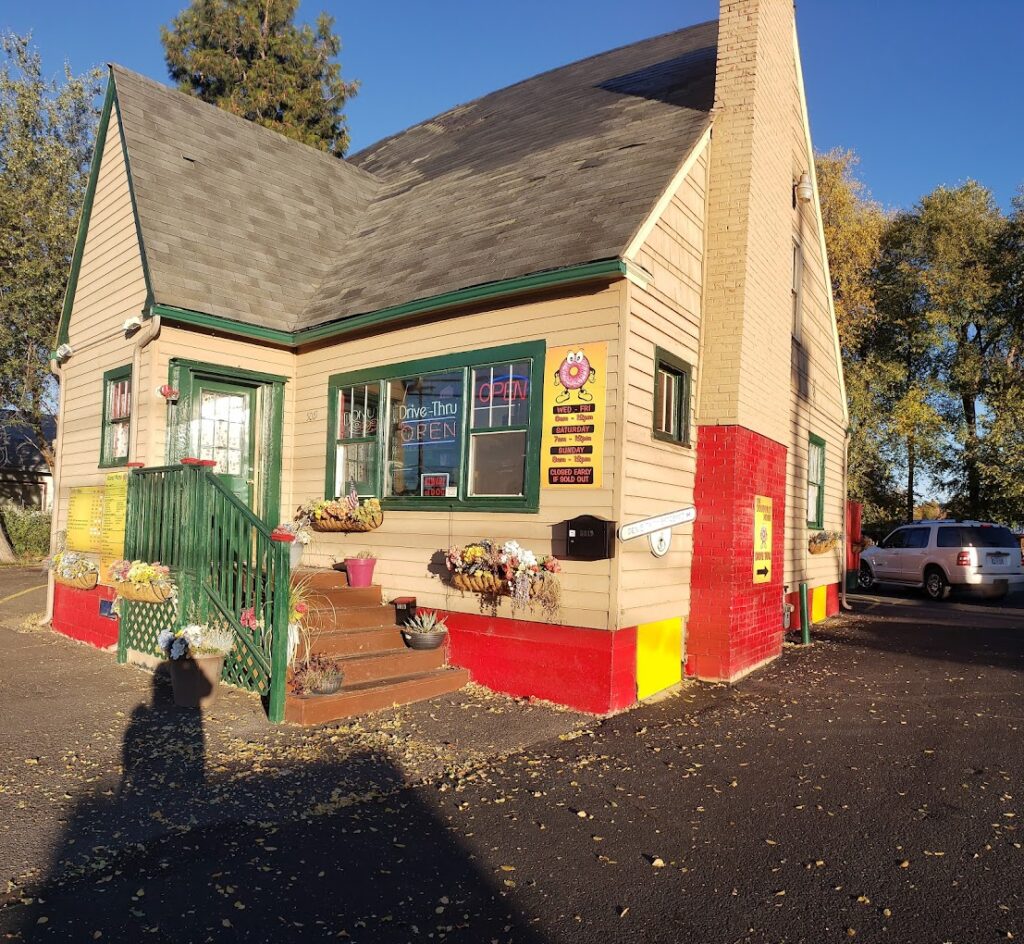 The outside of The Doughnut House. it's a tan house with green trim and a brown roof.