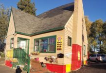 The outside of The Doughnut House. it's a tan house with green trim and a brown roof.