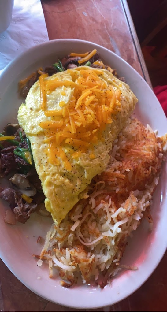A delicious looking omelet with cheddar and hash browns.