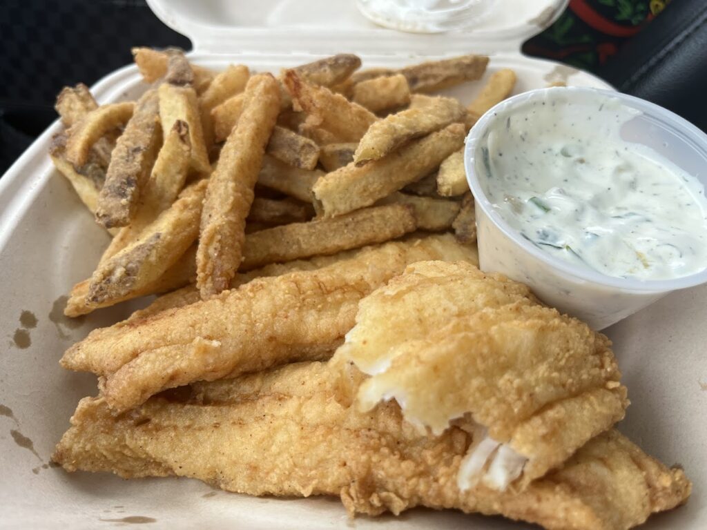 Fish and chips with a container of white dipping sauce at Woggy's.
