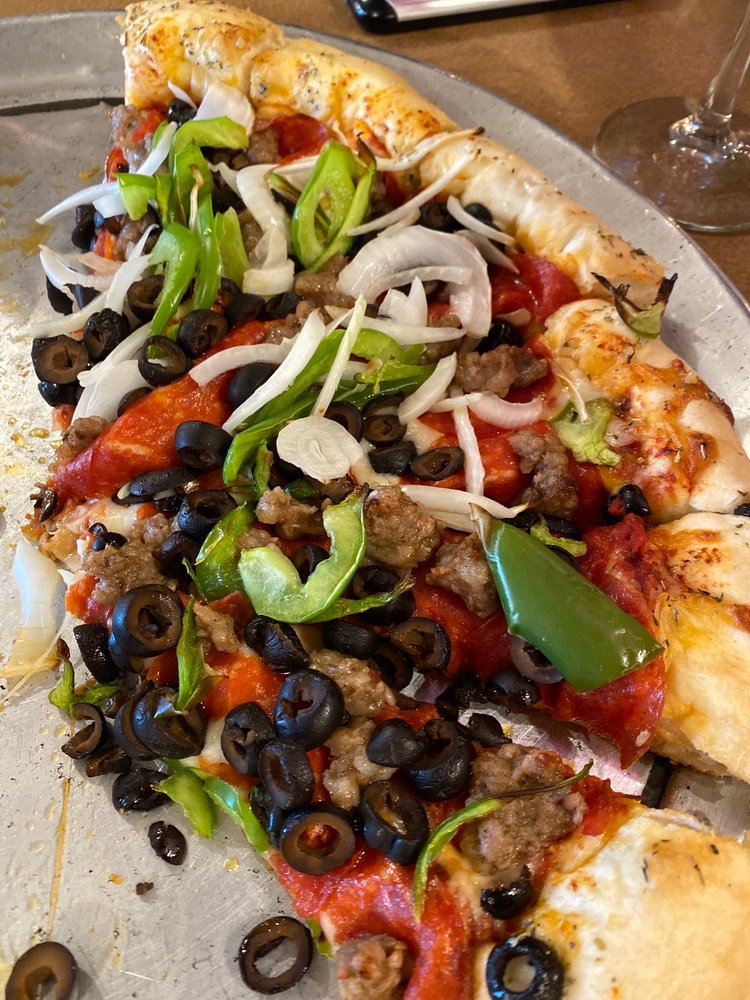 A pizza piled high with toppings like bell pepper, onion, olives, sausage and pepperoni.