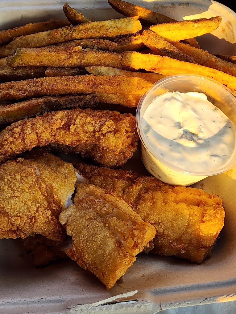 Fish and chips with a container of white dipping sauce.