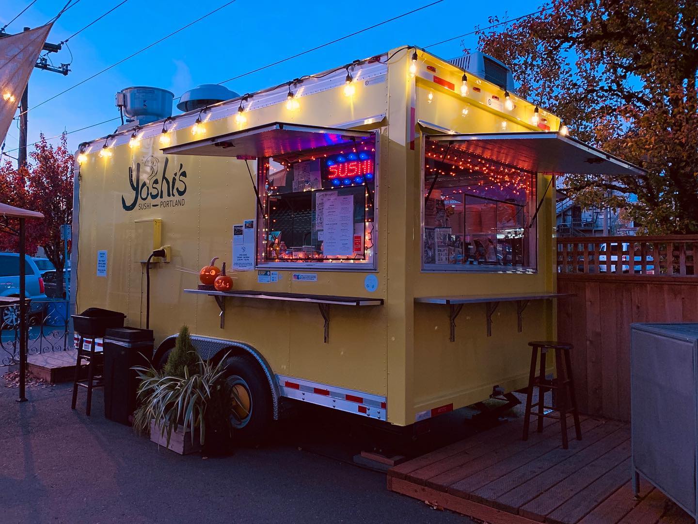 The Yoshi's Sushi food truck lit up at night.