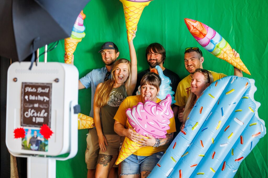 Several people pose in front of an ice cream photo station.