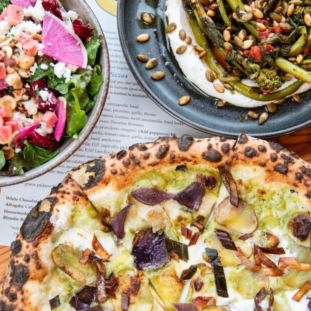 A gorgeous wood fired pizza with side dishes.