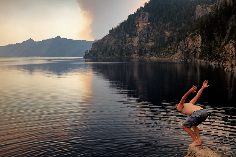 A person diving into Crater Lake from just above the water's surface.