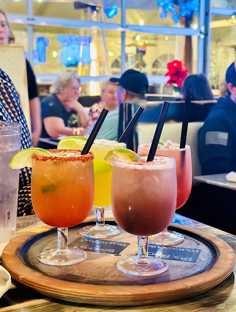 Various colorful alcoholic drinks on a tray.