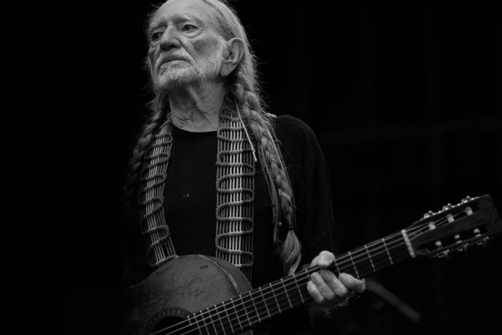 A black and white photo of Willie Nelson holding a guitar. Summer concerts, Oregon,  Things to do, 2024