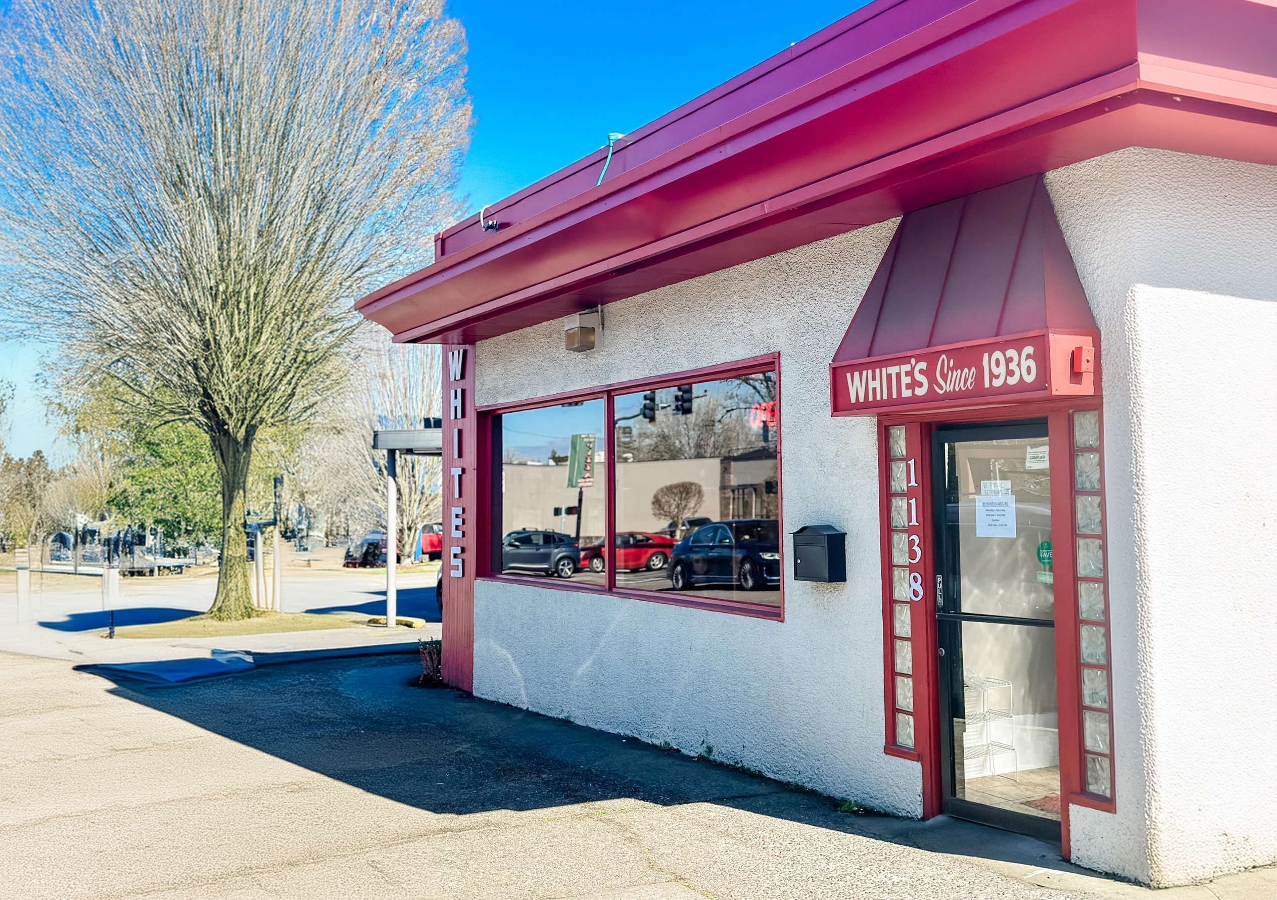 The outside of White's Restaurant. It's a white building with a red roof and red trim.