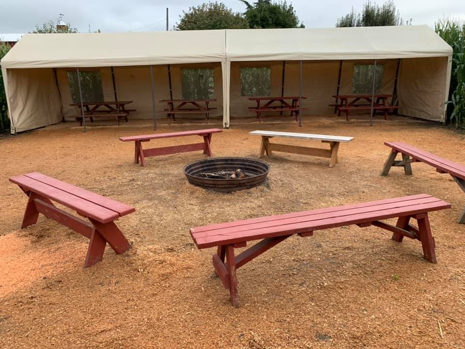 One of the rentable bonfire areas. There's covered seating, picnic tables, and red wooden benches surrounding a bonfire pit.