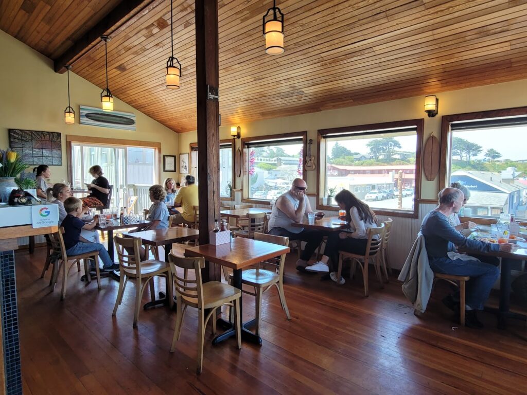 The interior of The Loft Restaurant And Bar. It has high wooden ceilings, warm wood floors, wood tables and chairs, and warm yellow lighting. It's a very cozy interior.