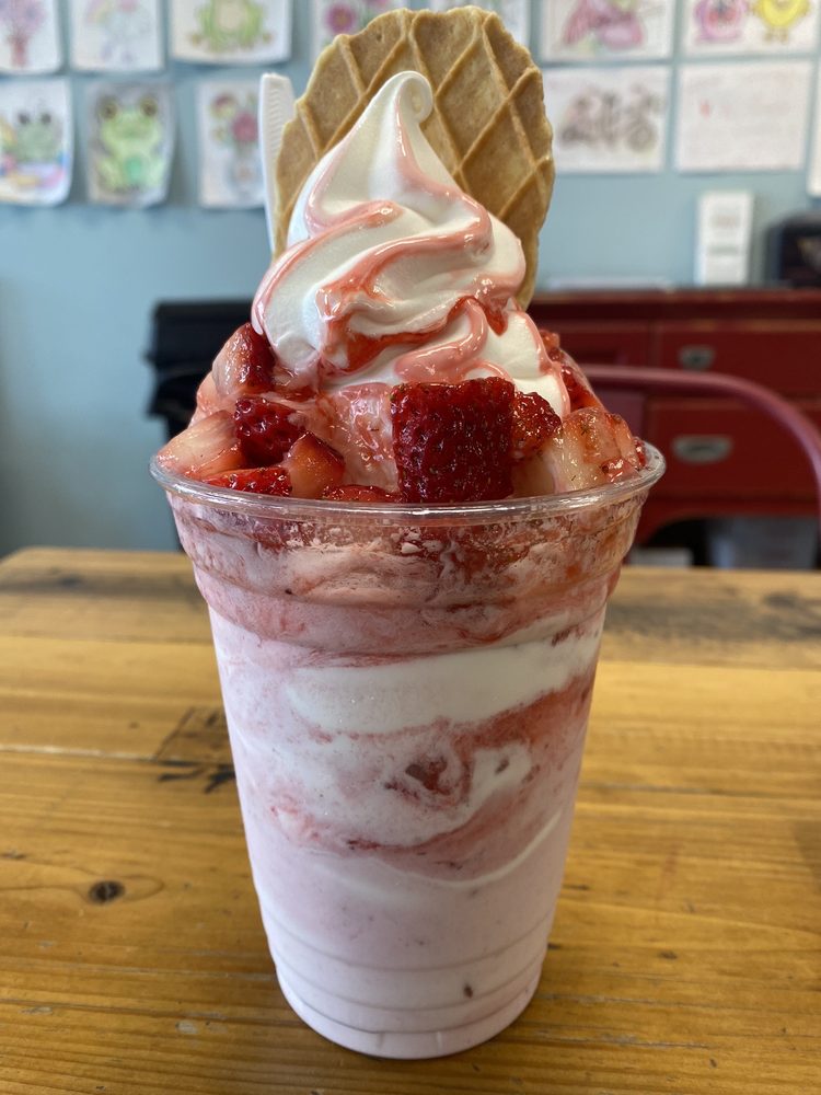 A tasty ice cream treat with soft serve, strawberries, and other toppings.