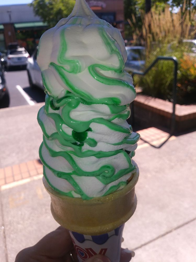 A delicious looking soft serve cone with green flavor ribbons.