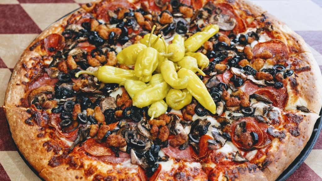 Pizza with pepperoncinis, olives, and meat.