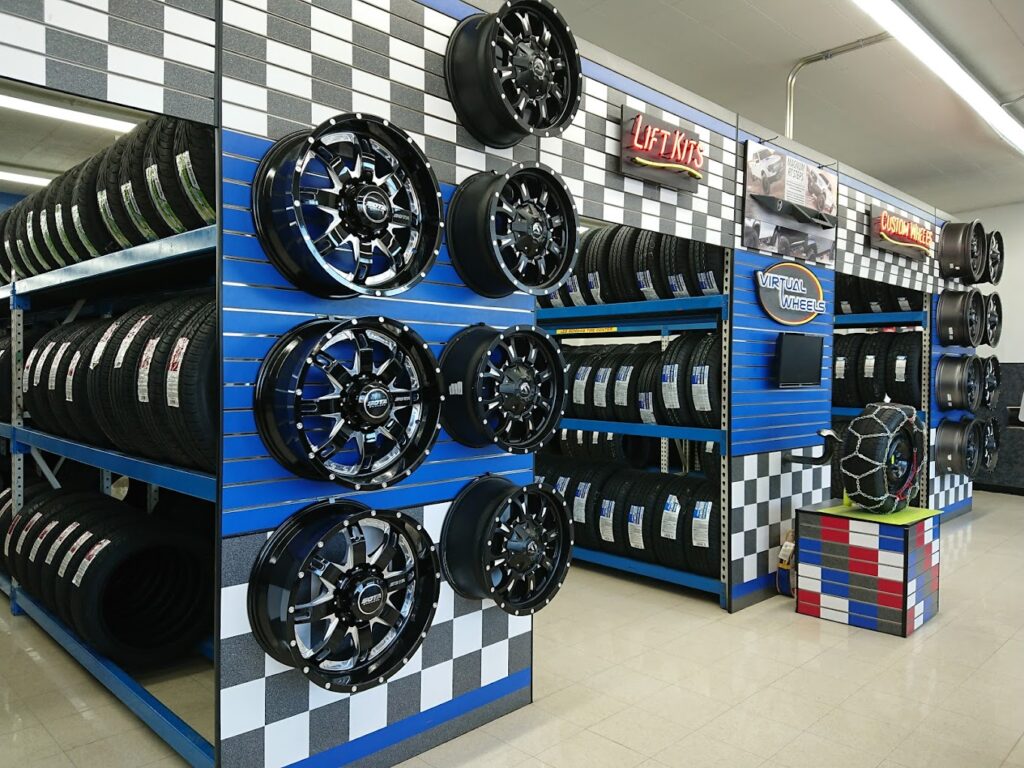 The interior of a Les Schwab tire center. There are blue shelves with a black and gray checkered pattern displaying tires and wheels.