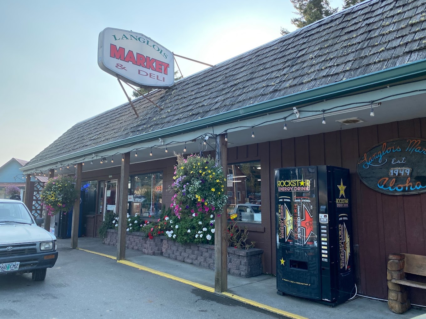 The outside of the Langlois Market. It's a brown building with a brown shingle roof, and green trim.