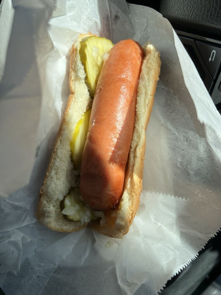 A hot dog in a bun with pickles.