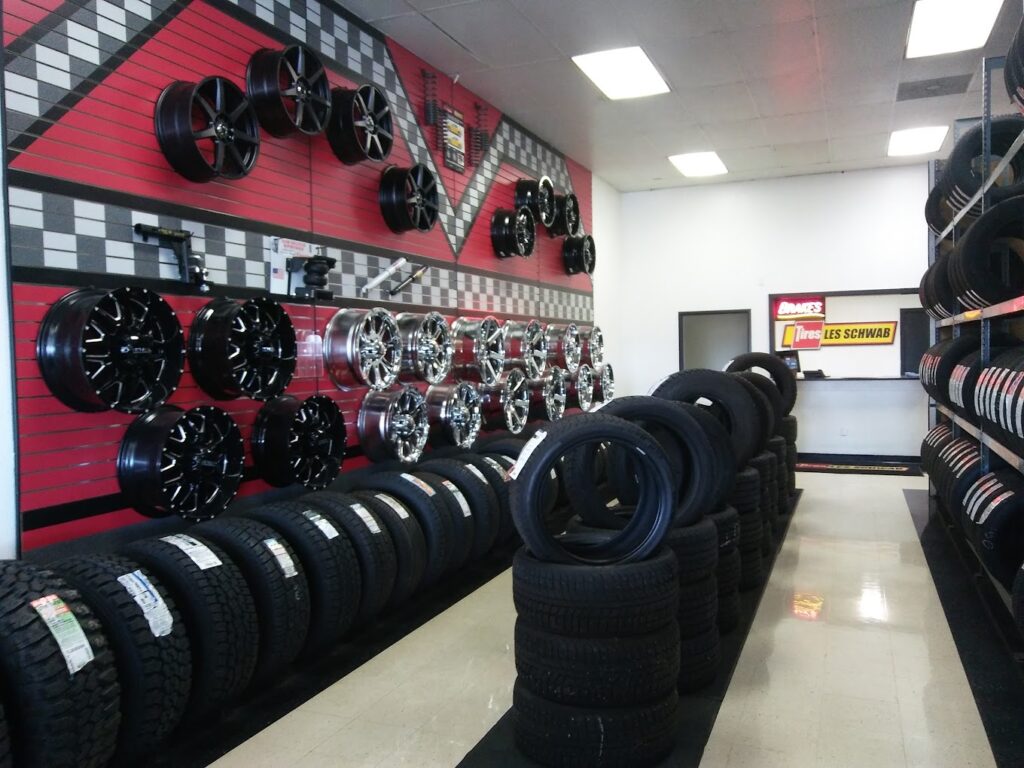 The interior of a Les Schwab tire store. there's a red wall, a white wall, and many tires and wheels on display.