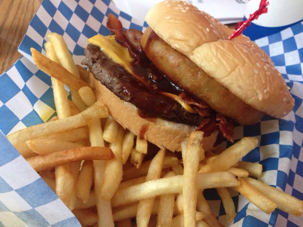 A burger and fries on a blue and white checkered paper food wrapper.