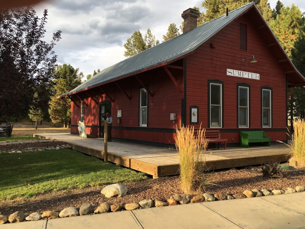 A red train station and wooden platform on a cloudy day.