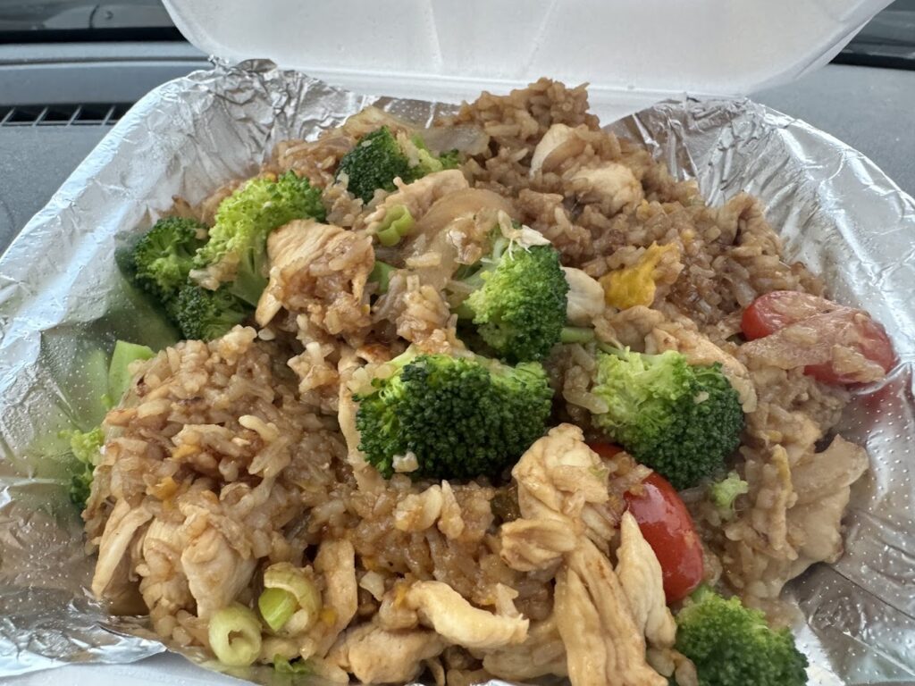 A white Styrofoam box filled with delicious looking Thai food.