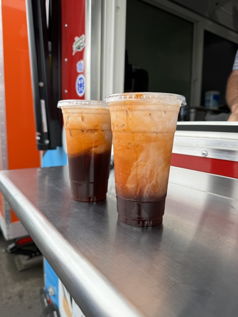 Two tall plastic cups filled with Thai iced tea.