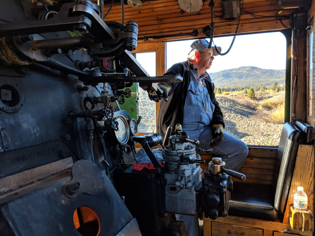 A conductor looks out the train window as he operates equipment.