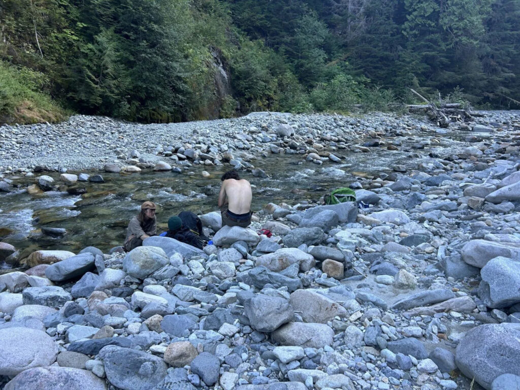 Men sit on the banks of a river during a rescue mission.