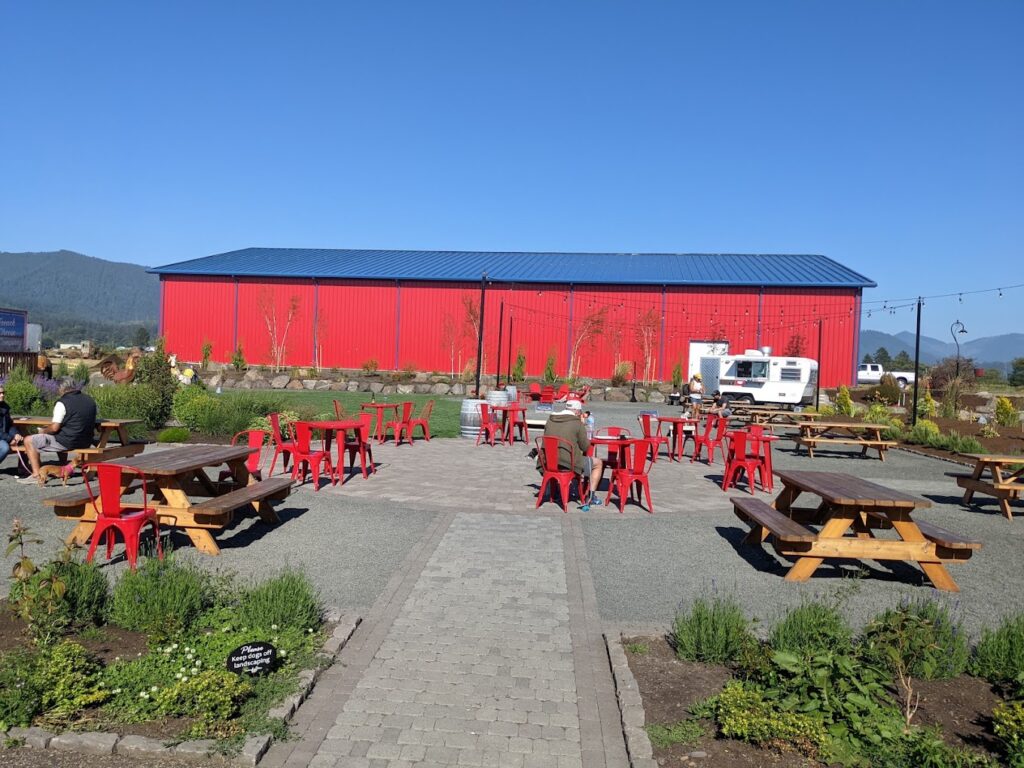 The outdoor seating area at Blue Heron French Cheese company. It features a pathway and lots of outdoor seating in a scenic setting.