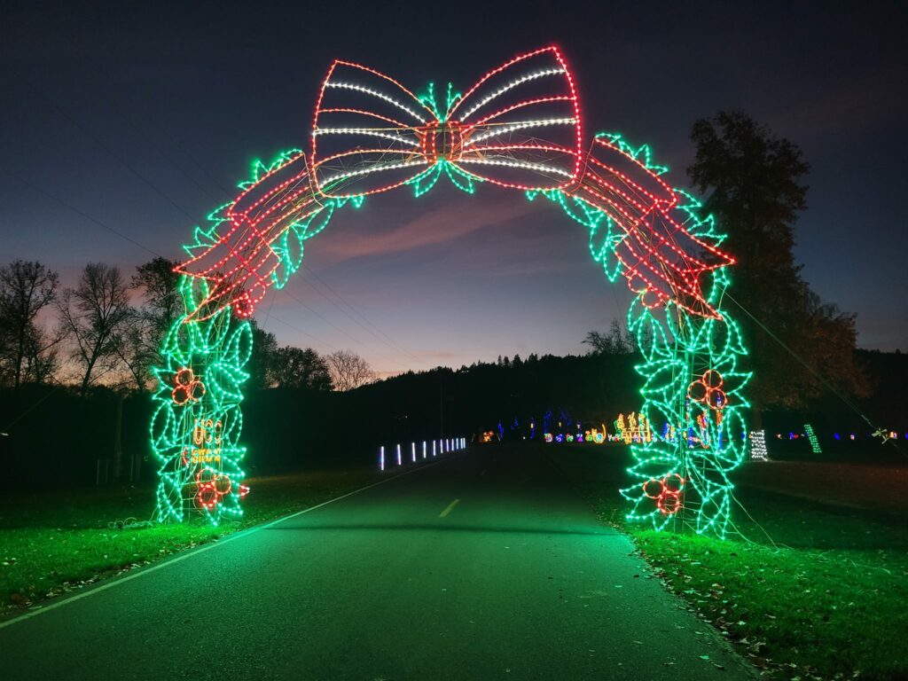 A large wreath made of Christmas lights goes over a road.