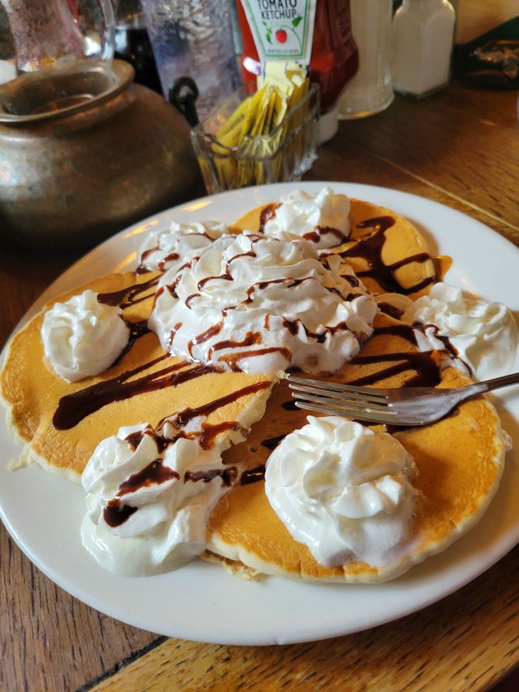 Pancakes with whip cream and a chocolate drizzle. They look tasty!