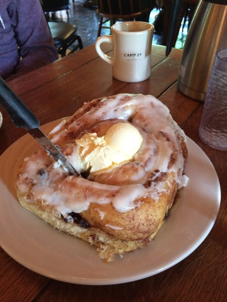 A giant cinnamon roll with butter on top and a knife sticking out of it.