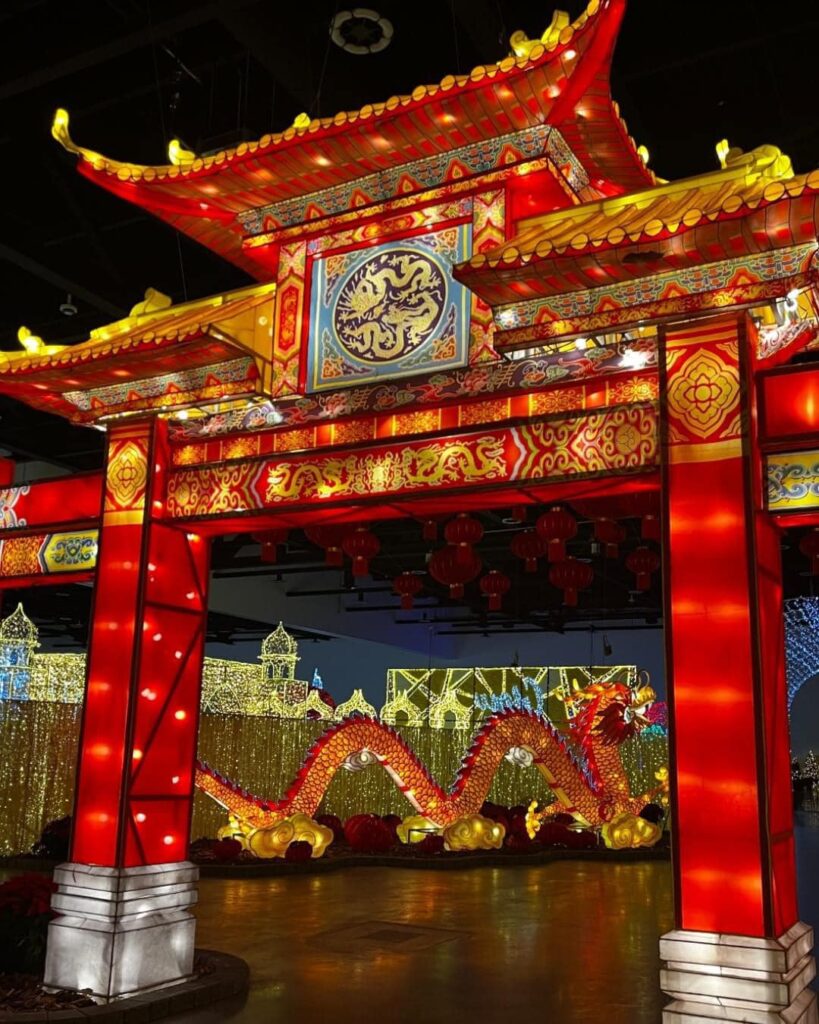 A huge red and gold Asian gate with a red Chinese dragon in the background.