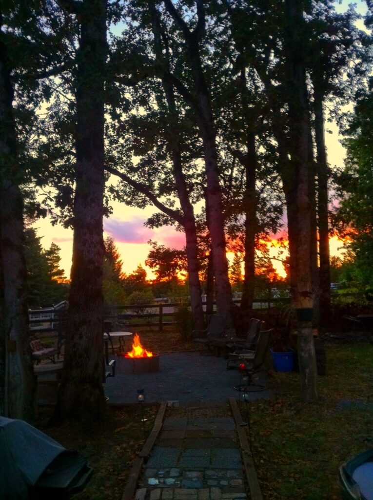 Sunset over a fire pit in the trees at the Owl's Nest Inn.