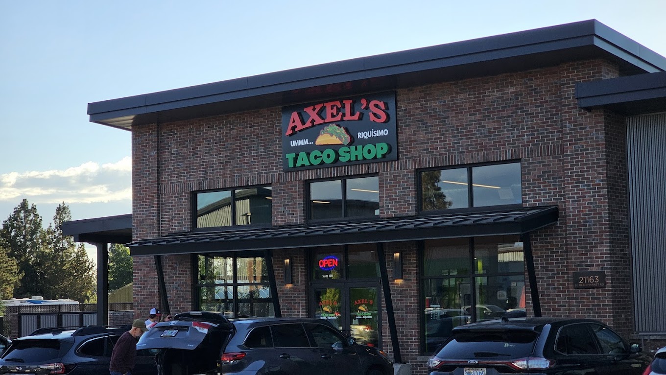 The outside of Axel's Taco Shop. It's a brick building with a large red and green sign on the front.