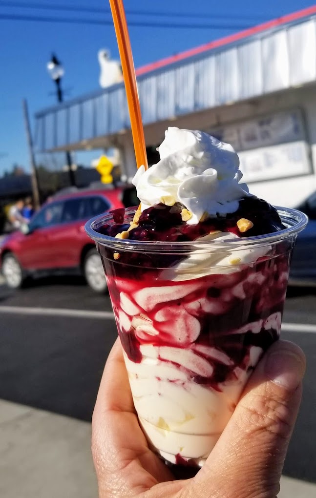 A milkshake full of fruit and topped with whip cream.