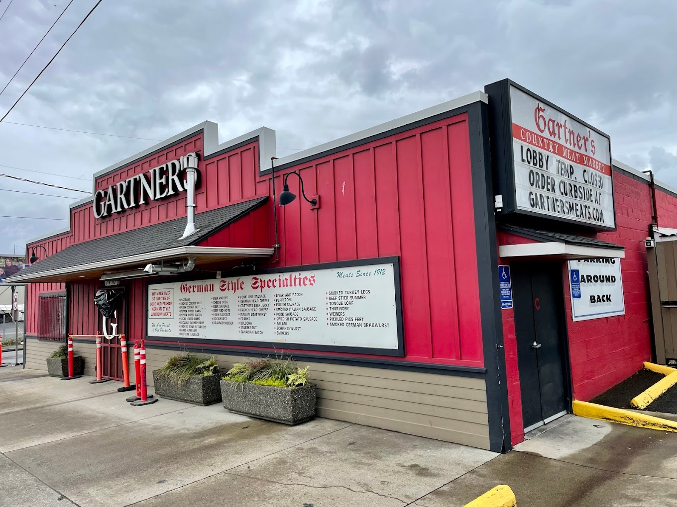 The outside of Gartner's Meats. It's a red building with a white sign out front listing the wide variety of meats that they sell.