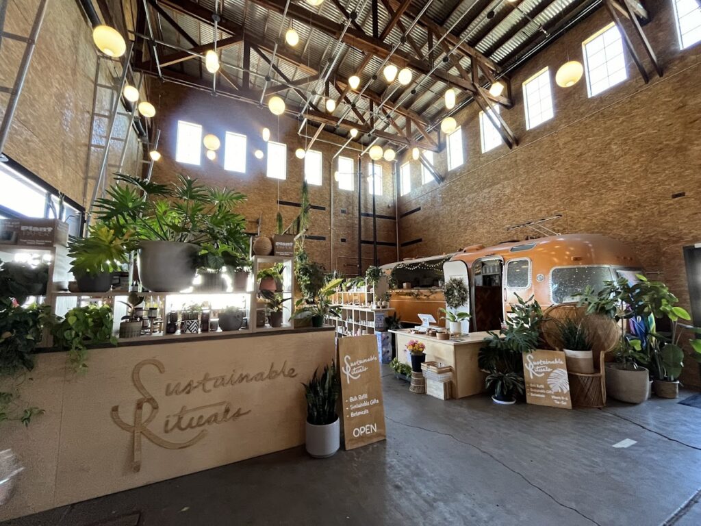 Plants and other goods for sale inside the hip Mac Market in McMinnville, Oregon. An old orange Airstream Trailer adds to the atmosphere behind the plants.