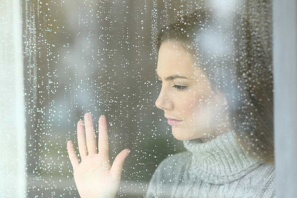 poor woman looking outside at the rain