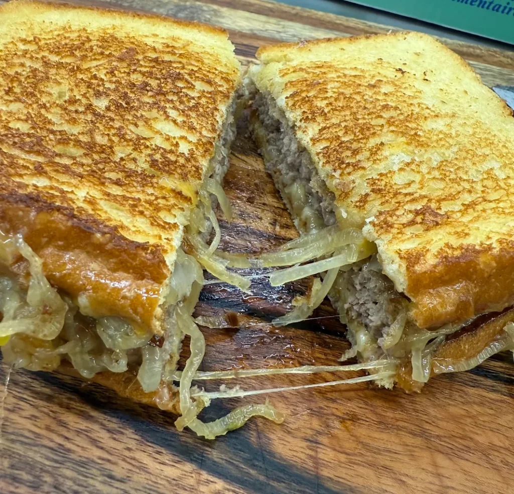 A crazy good looking patty melt sandwich, cut in half.