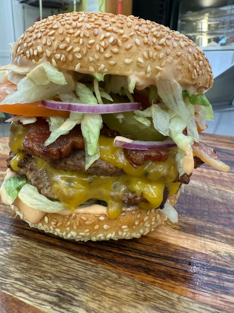A cheeseburger stacked so high with meat, cheese and veggies that it looks like it might topple over. Looks really tasty!