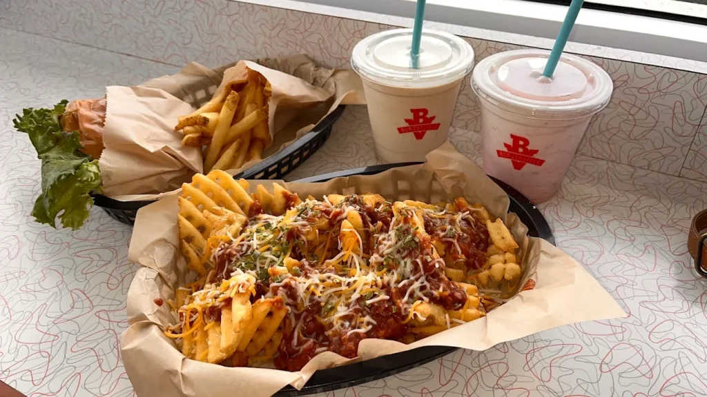 Delicious criss cut fries loaded with toppings at Burgerville. Two milkshakes sit in the background.