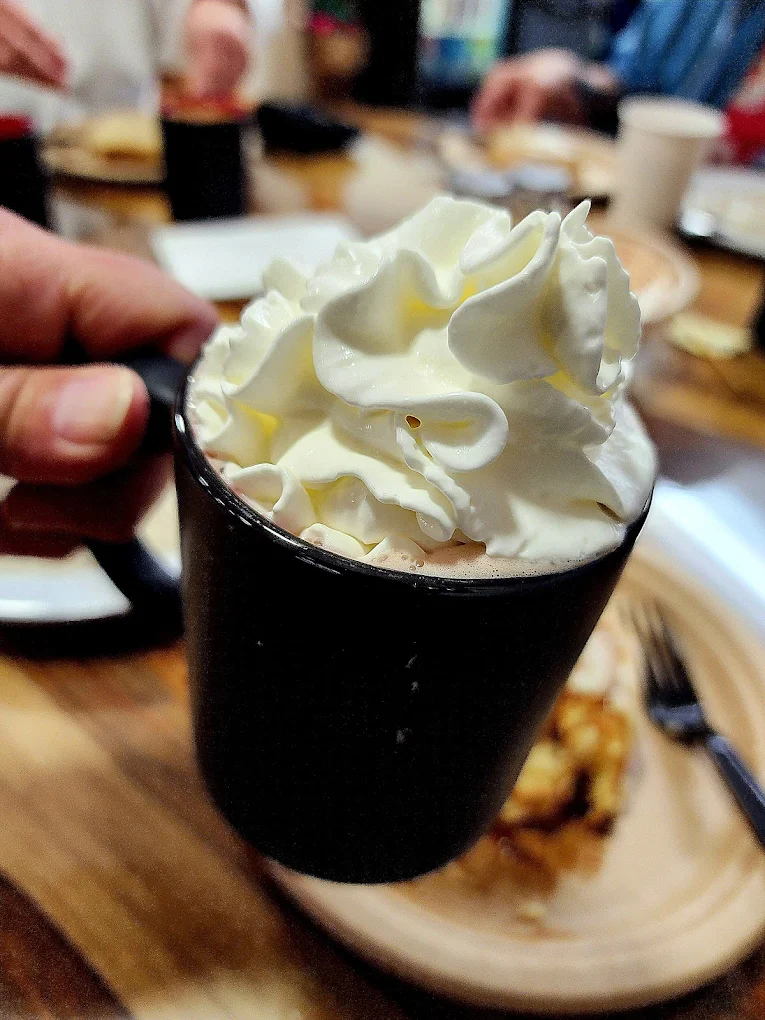 A hot drink in a black mug topped with whipped cream.
