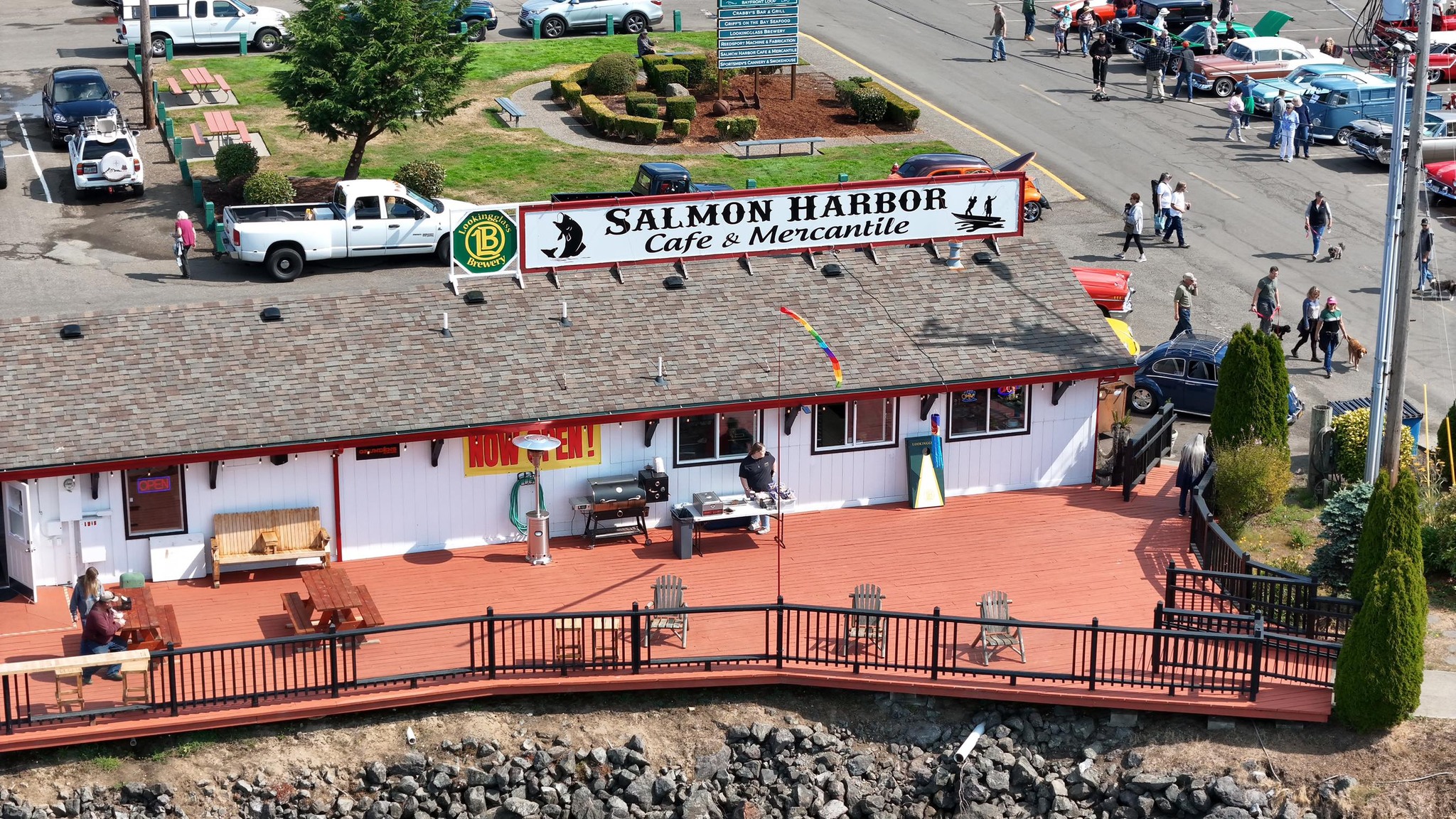 An aerial photo of Salmon Harbor Cafe and Mercantile. It's a white building with a gray roof, and a large white sign with black letters and a red border.