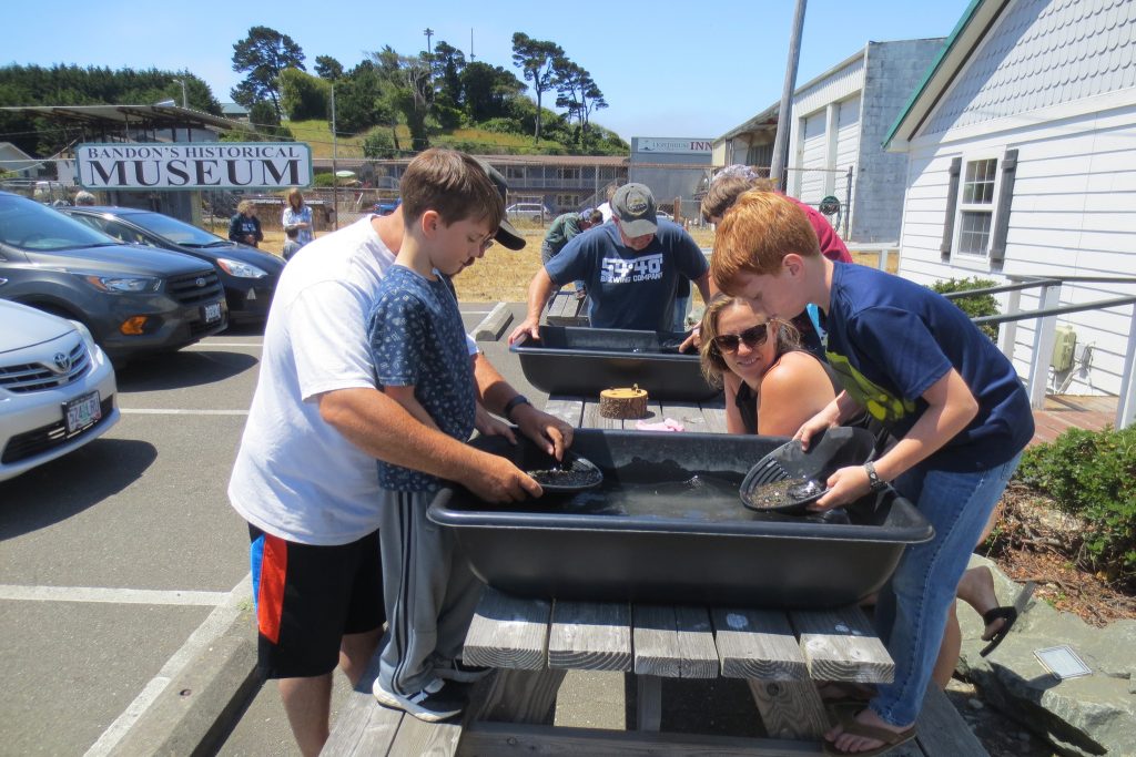 Children learn to gold pan in a basin of water set up outside the museum on special days.
