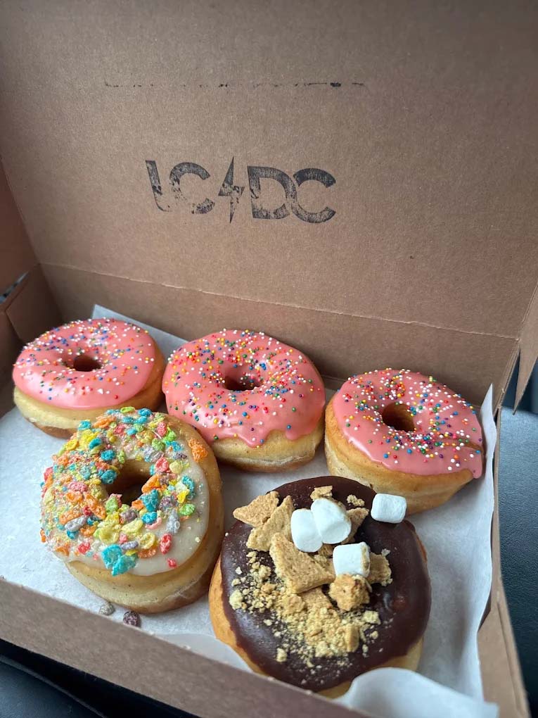 An assortment of colorful delicious fresh donuts in a box.