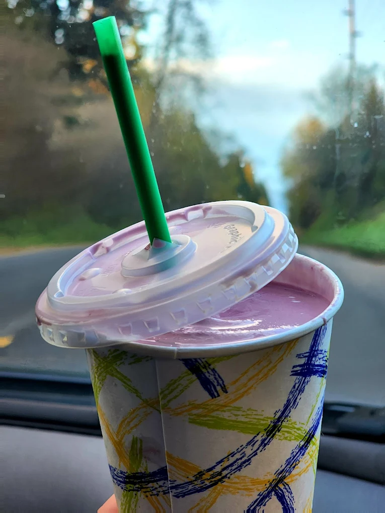 A pink milkshakes in a to-go cup.