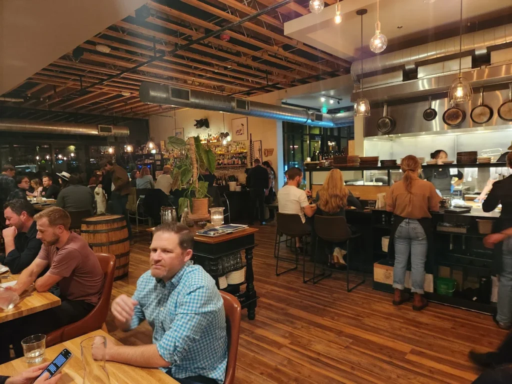 The interior of Rancher Butcher Chef in Bend, Oregon. Warm wood, modern chairs and décor make it a welcoming place to dine. In the photo, people sit and eat.